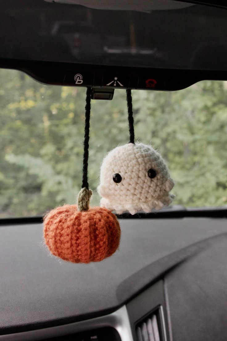 two crocheted pumpkins hanging from the dashboard of a car