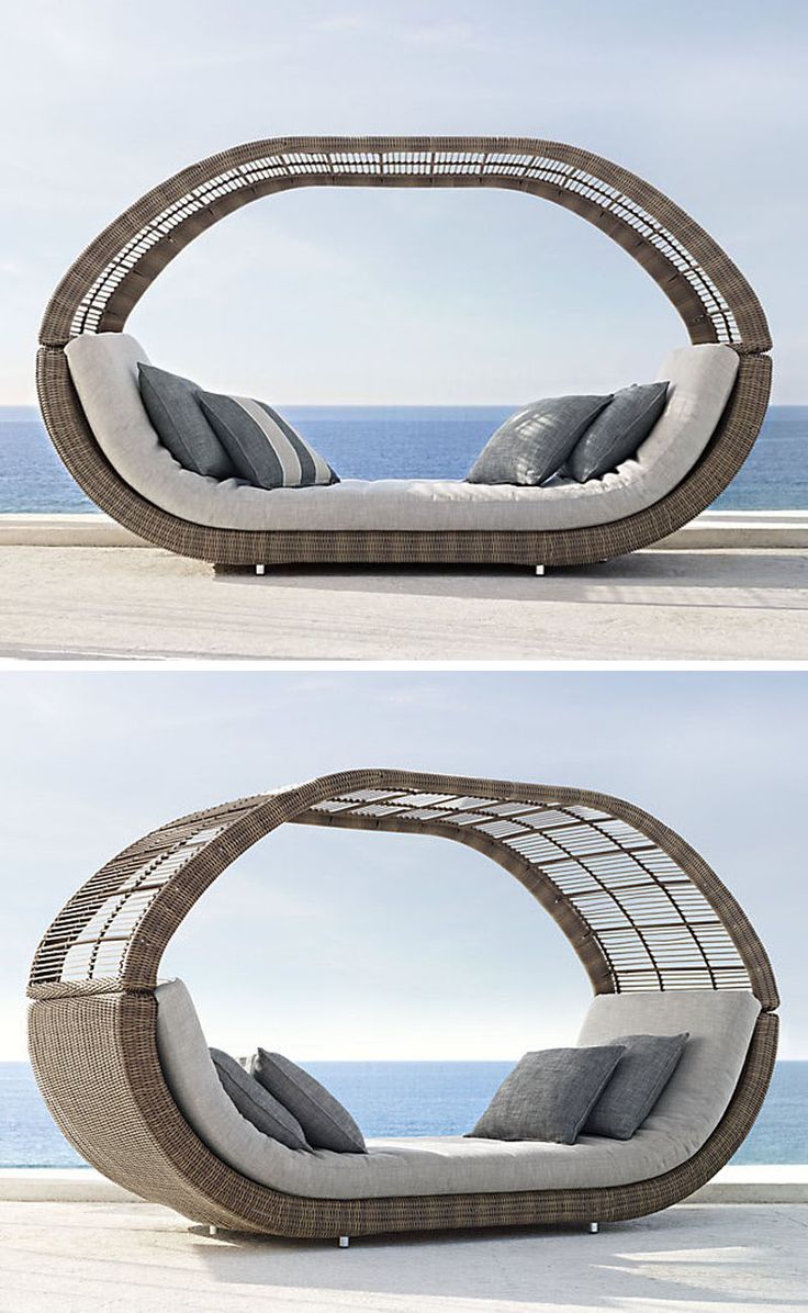 an outdoor day bed with pillows on the top and bottom, in front of the ocean