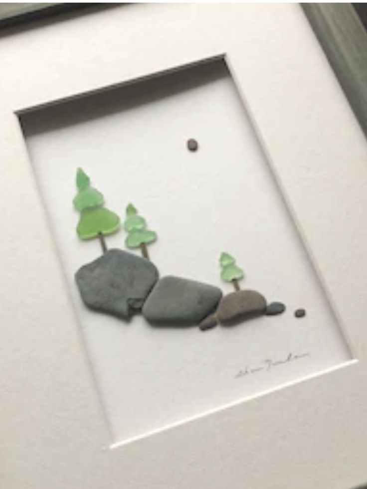 there is a picture frame with rocks and trees in the middle, on top of a table