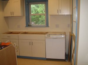 an empty kitchen with white cabinets and blue trim on the window sill above the dishwasher