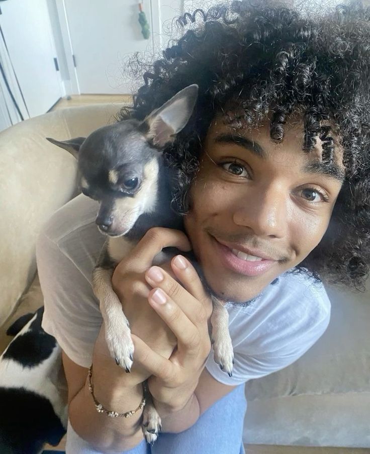 a woman holding a small dog in her arms and smiling at the camera while sitting on a couch