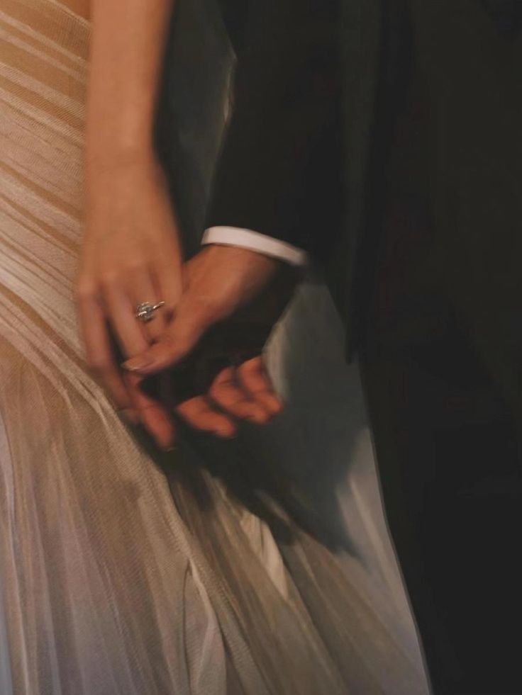 a close up of a person wearing a ring on their wedding day holding the hand of another person's dress