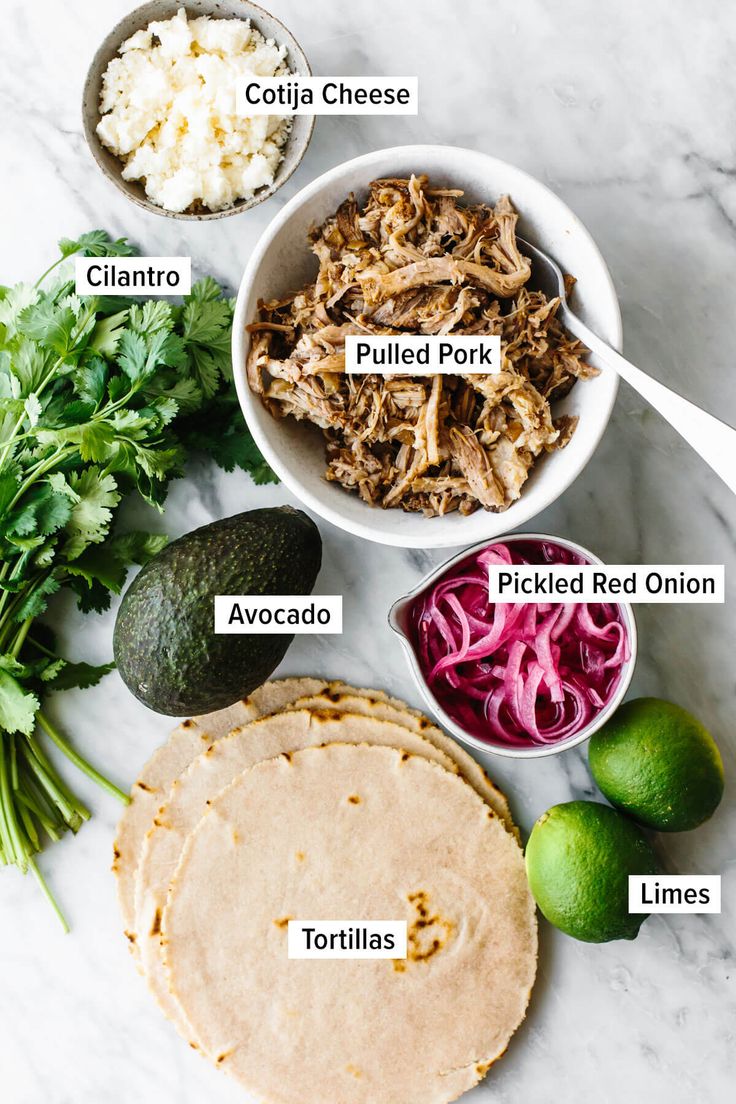 ingredients to make pulled pork burritos laid out on a white marble counter top