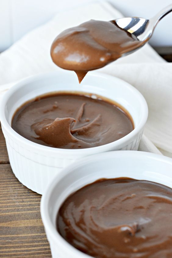 two white bowls filled with chocolate pudding on top of a wooden table