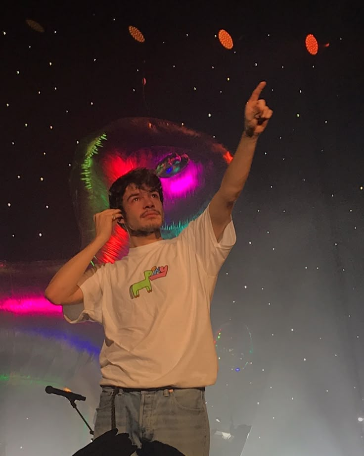 a man standing on top of a stage holding a cell phone up to his ear