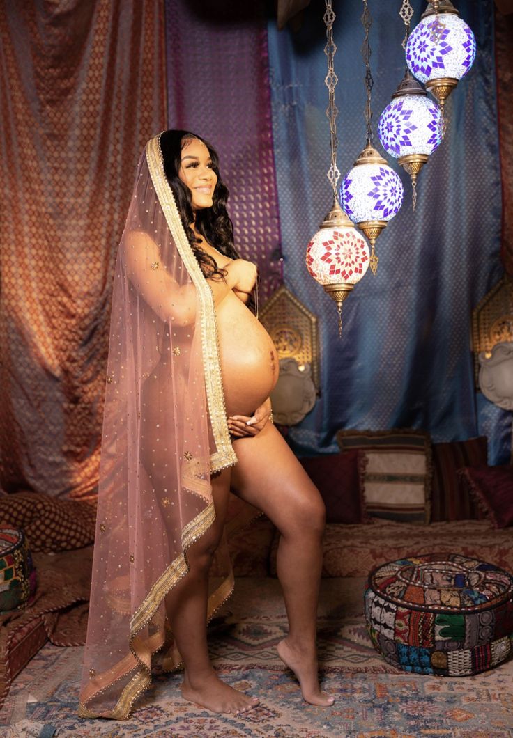 a pregnant woman wearing a veil poses for a photo in front of some lights and decorations