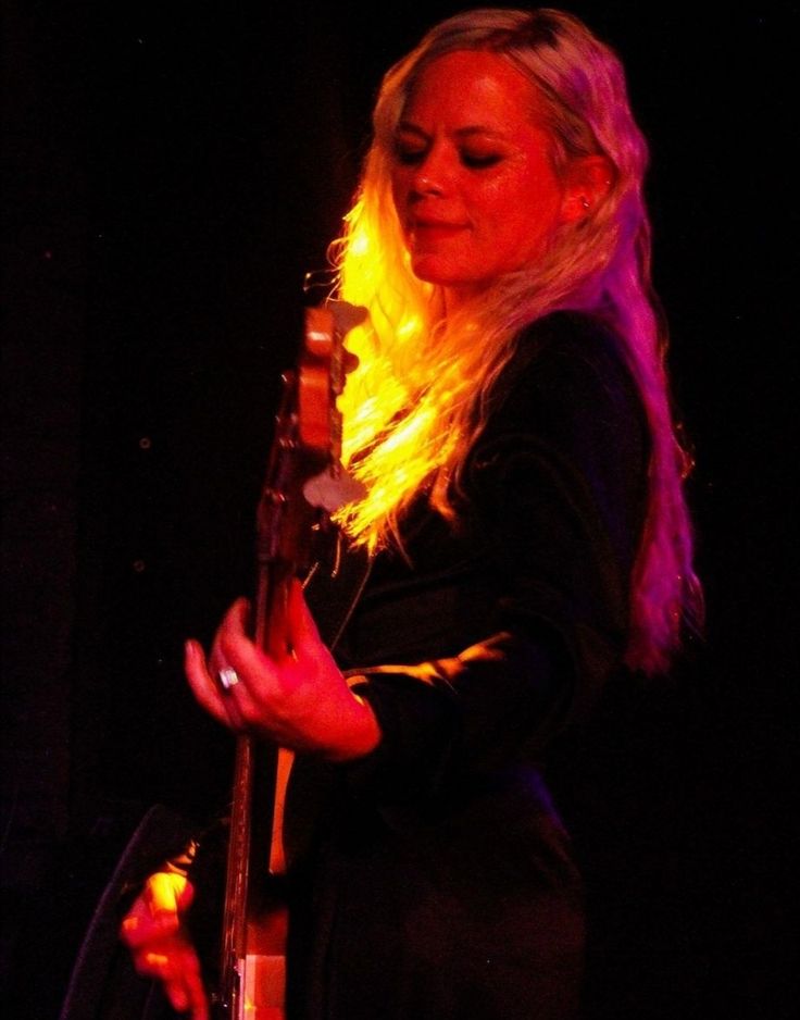 a woman with long blonde hair holding a guitar