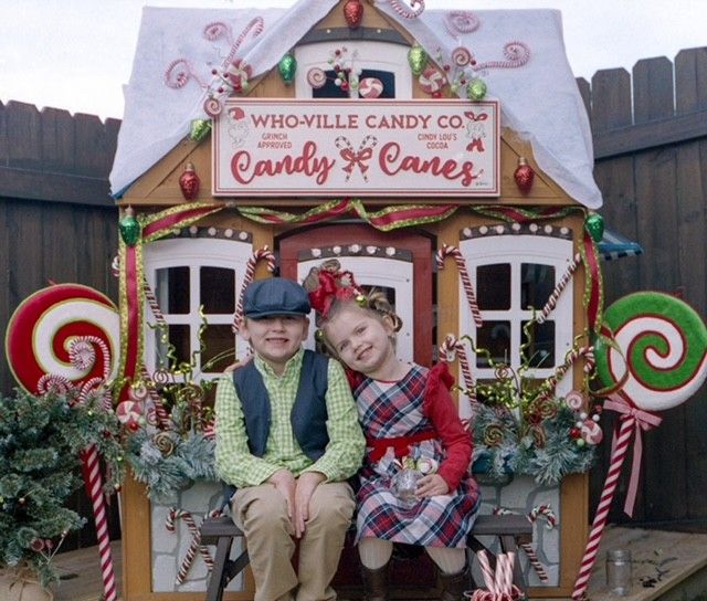 two children and a dog sitting in front of a candy house