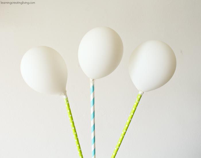 three white lollipops in a blue vase with green and white striped straw