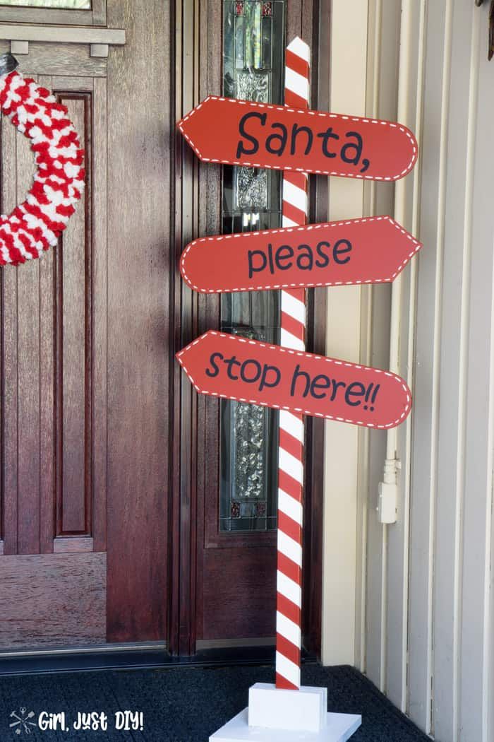 a red and white sign sitting on the side of a door next to a wreath