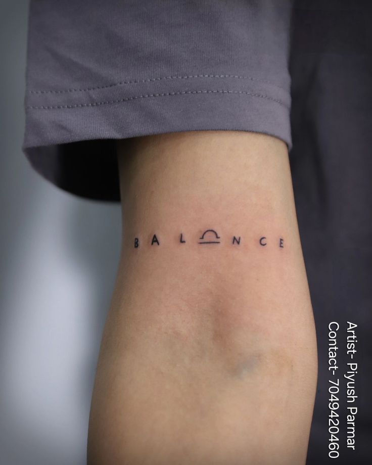 the word balance written in cursive font on someone's lower back leg