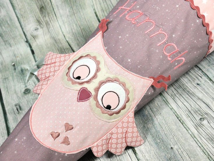 an owl pillow sitting on top of a wooden floor next to a pink and brown pillow