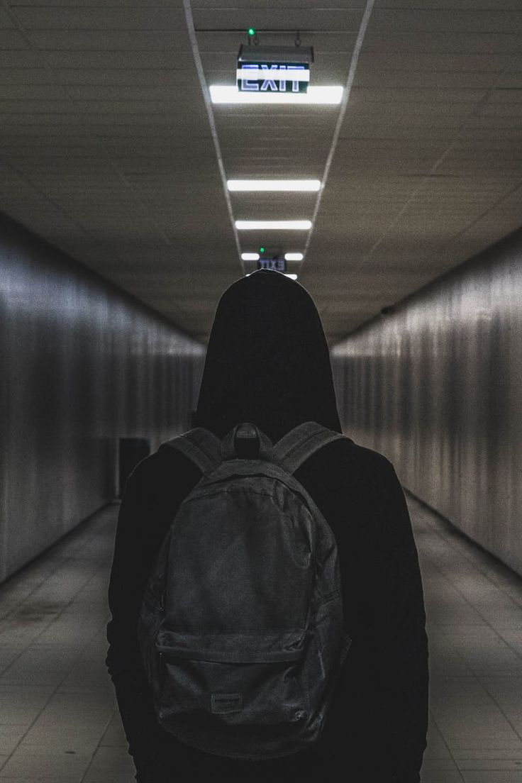 a person with a backpack walking down a long hallway lined with metal walls and lights