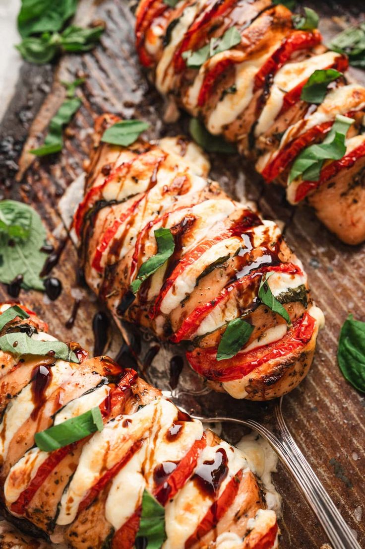 grilled chicken covered in sauce and garnished with fresh basil on a wooden board