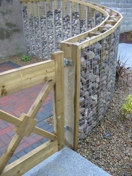 a wooden gate with rocks in it and a brick walkway leading up to the entrance