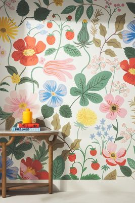 a table with books on it in front of a flower wallpapered wall and floor