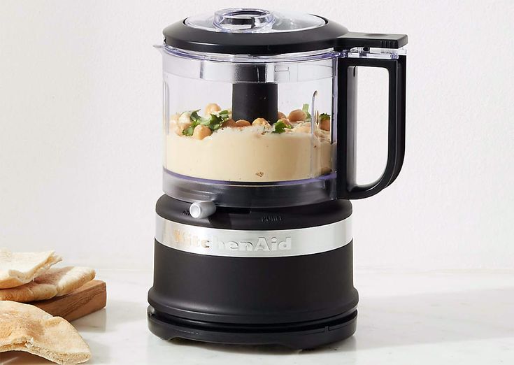 a food processor sitting on top of a counter next to crackers and an apple