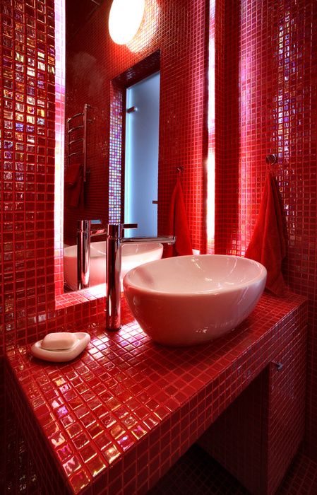 a bathroom with red tiles on the walls and a white bowl sink in the middle