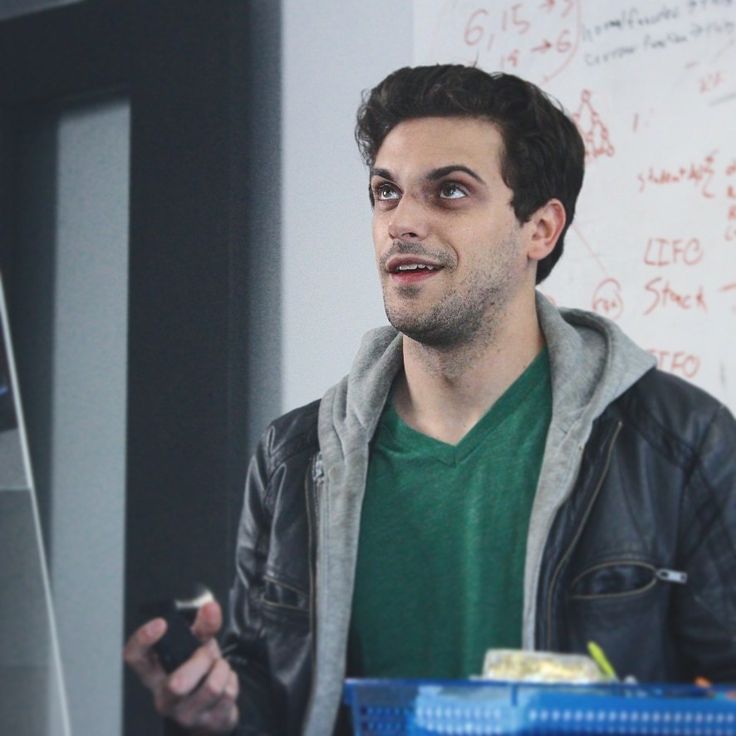 a man standing in front of a whiteboard with writing on the wall behind him