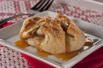 an apple pie on a white plate with caramel sauce drizzled over it