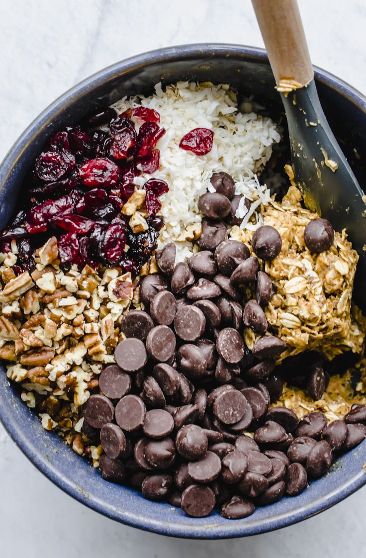 a bowl filled with granola, raisins, chocolate chips and cranberries