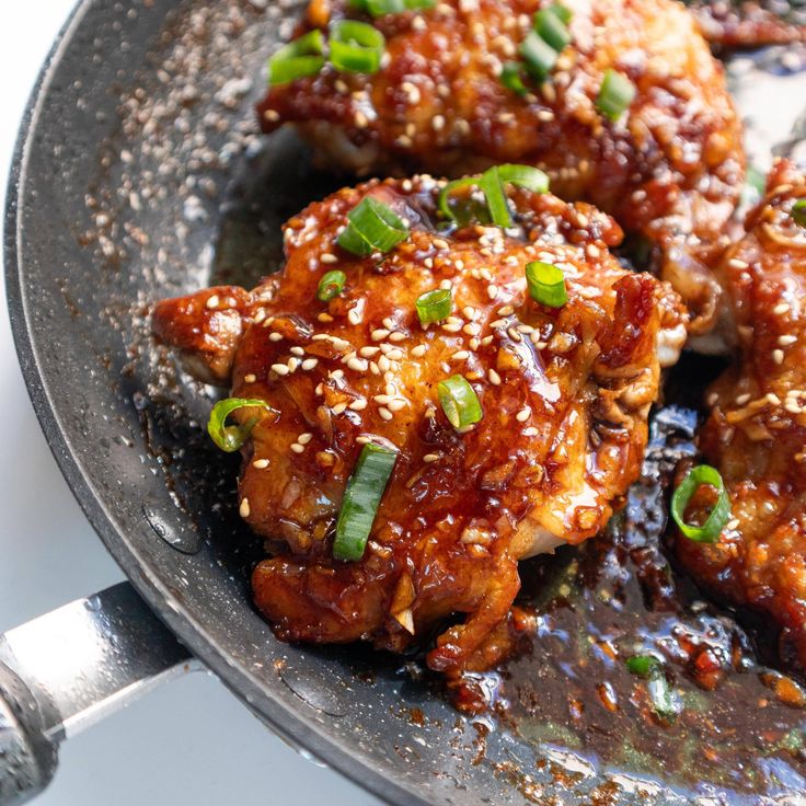 chicken wings with sesame seeds and green onions in a skillet