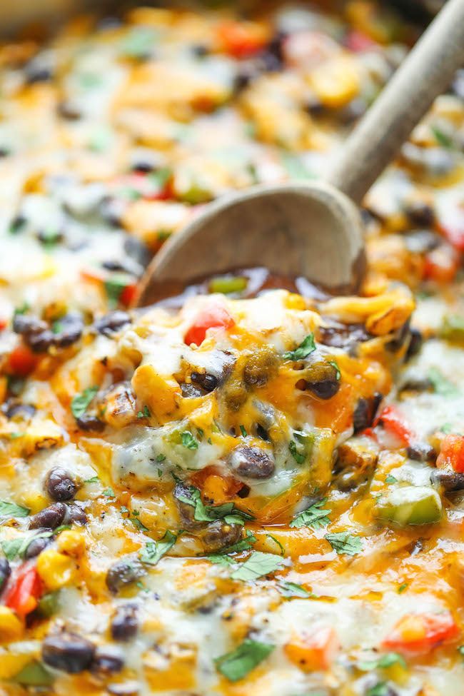 a close up of a spoon in a casserole with black beans and cheese