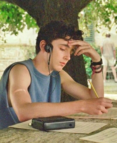 a young man wearing headphones sitting at a table with papers and a cell phone