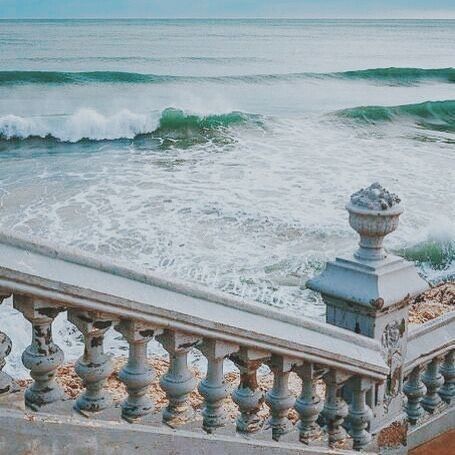 an ocean view with waves coming in from the water and on top of some railings