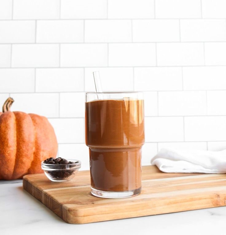 there is a cup of coffee on the counter next to some pumpkins and spices