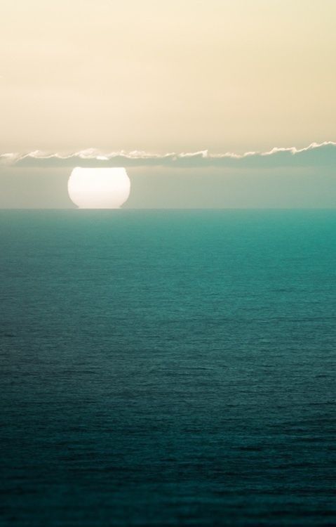 the sun is setting over the ocean and it looks like something from another planet in the sky