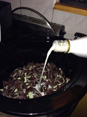 a person pouring milk into a crock pot filled with chocolate and marshmallows