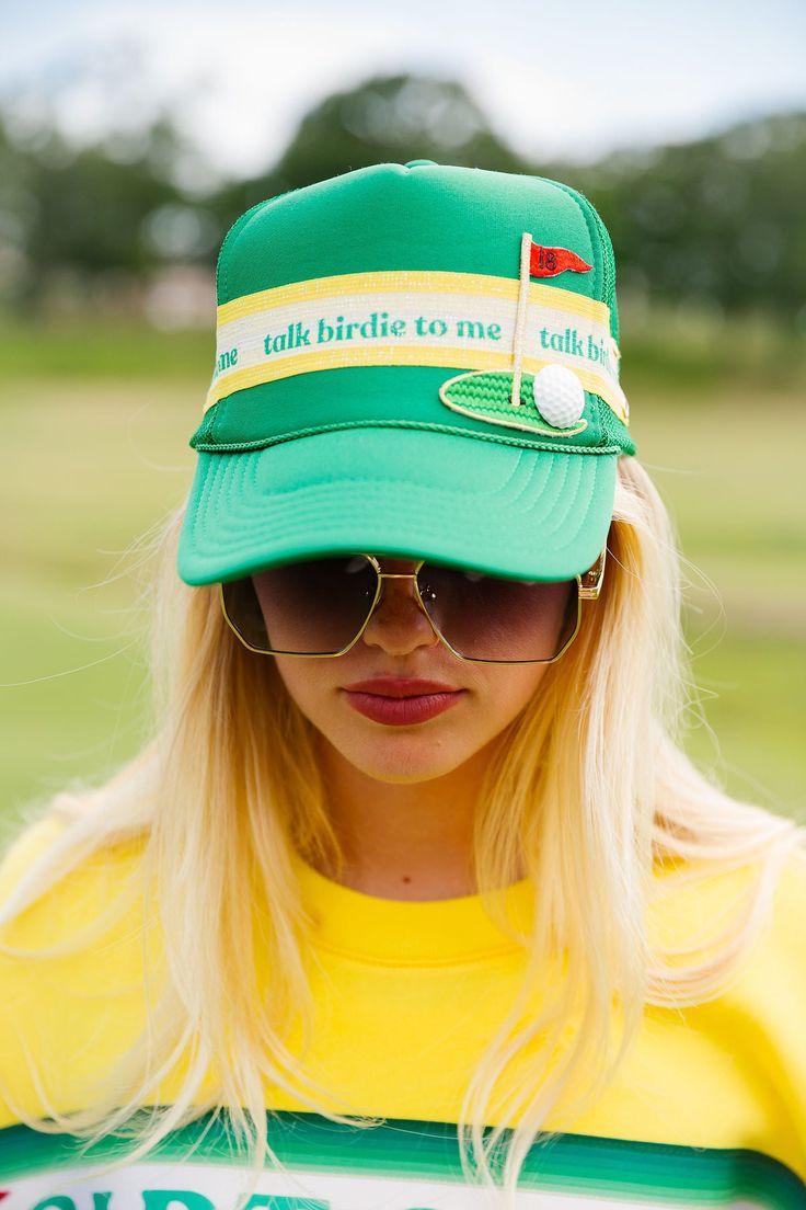 Add some personality to your golf game with our Talk Birdie To Me trucker hat. The green color and yellow/white striped ribbon are a fun twist on a classic look, and the 18th hole golf patch adds a touch of charm. Let your hat do the talking on the course! All orders are currently shipping within 14 business days. To receive item quicker, expedited shipping is available at checkout. Fun Green Trucker Hat For Summer, Green Visor Trucker Hat For Sports Events, Spring Green Trucker Hat For Sports, Green Trucker Hat With Visor, Adjustable Green Hat For Golf, Green Trucker Visor Hat, Green Baseball Cap For Golf, Adjustable Green Golf Hat, Retro Green Visor Baseball Cap