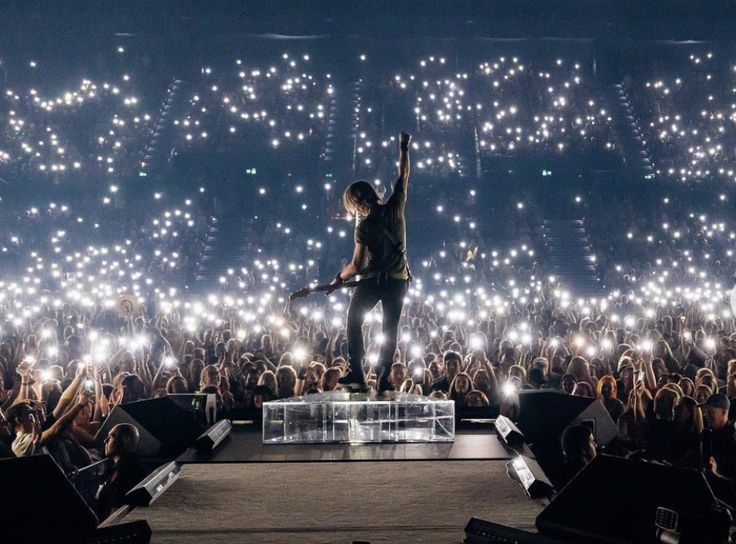 a man standing on top of a stage with his arms in the air and lights behind him