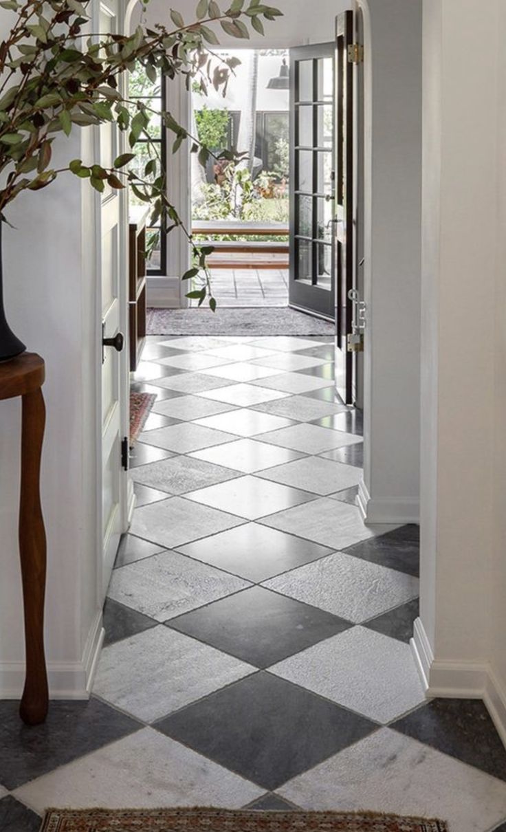 an entry way with tiled flooring and a potted plant on the far side