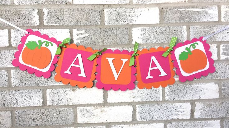 an orange and pink banner hanging from a brick wall with the word ava on it