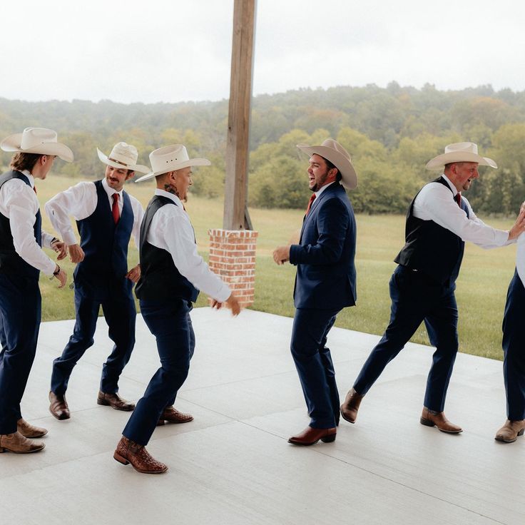 a group of men in suits and hats dancing on a porch with trees in the background