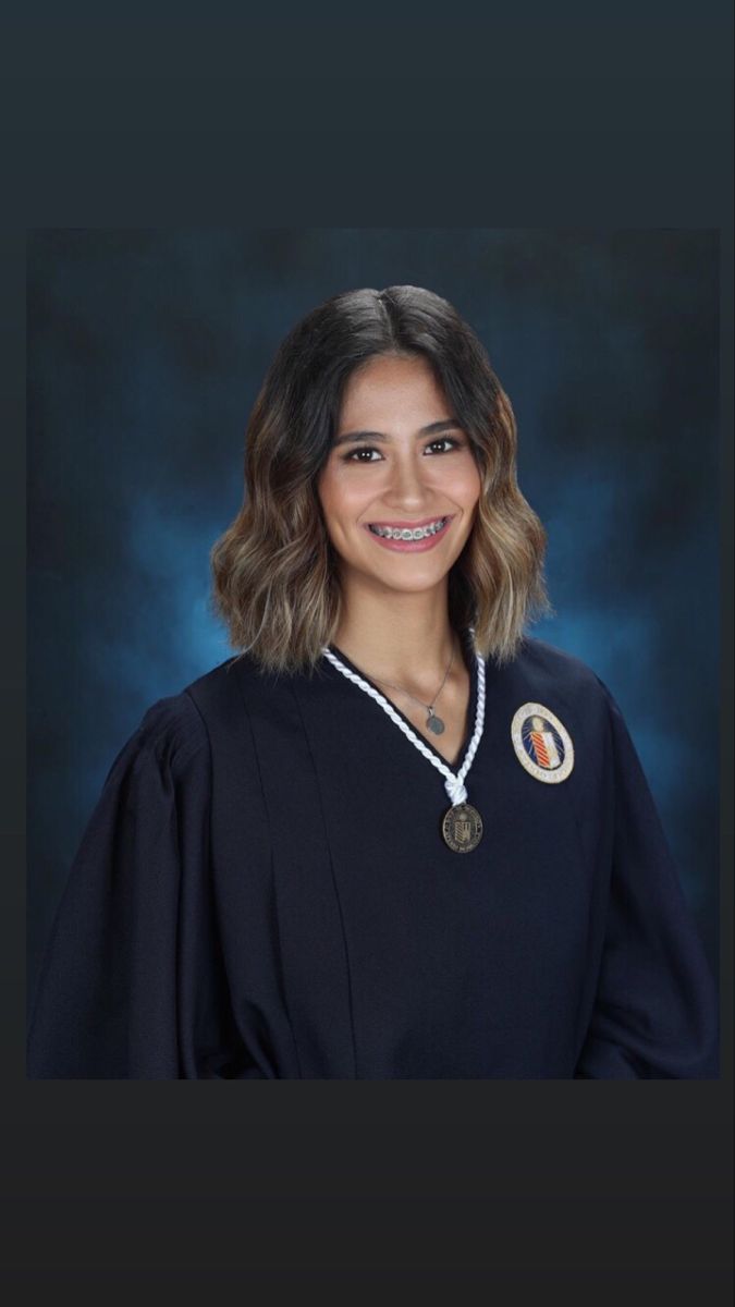 a woman in a black graduation gown with a medal on her neck and necklace around her neck