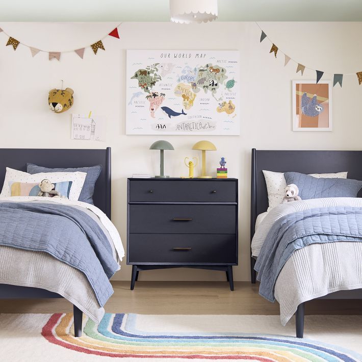 two twin beds in a bedroom with colorful rugs and artwork on the wall above them