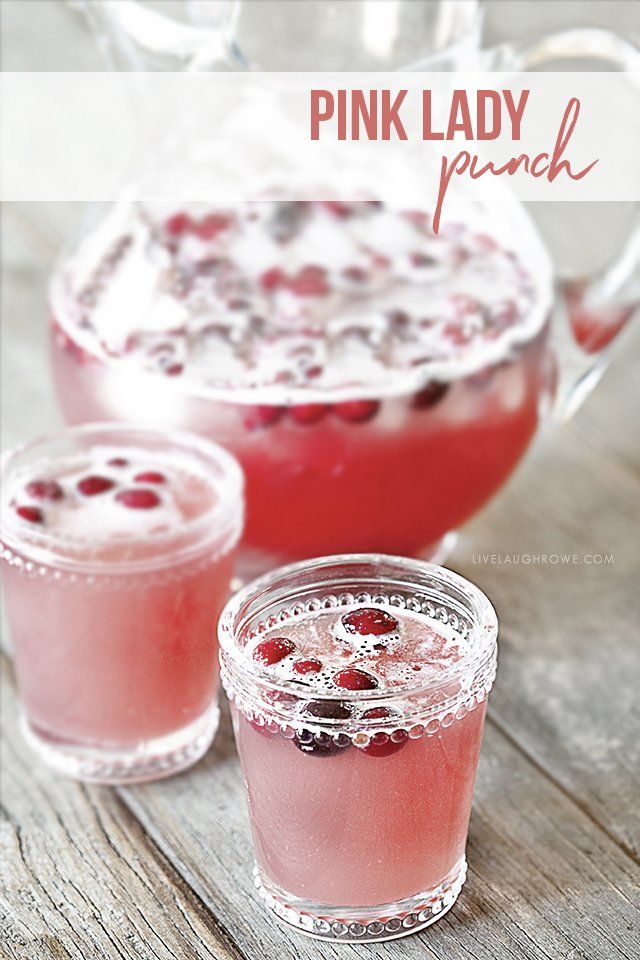 two glasses filled with liquid and garnished with cranberries next to a pitcher