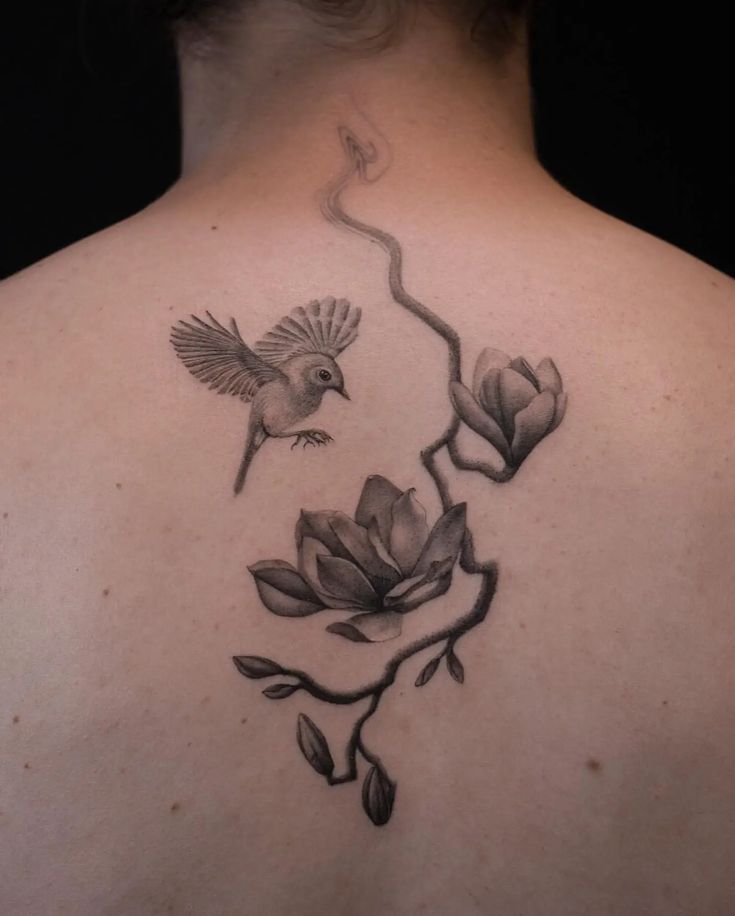 the back of a woman's neck with flowers and birds on it, in black and white