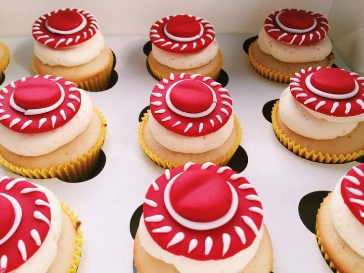 cupcakes decorated with red and white icing in a box