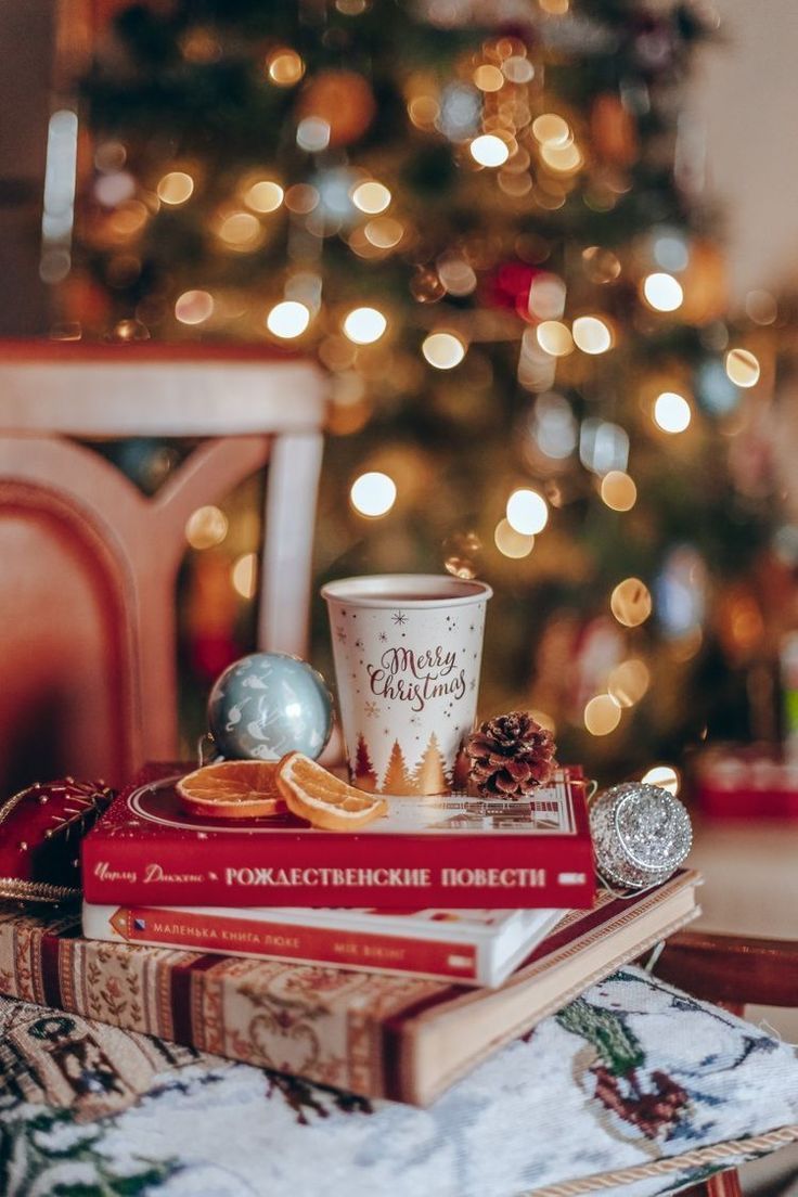 a stack of books sitting on top of a wooden table next to a christmas tree