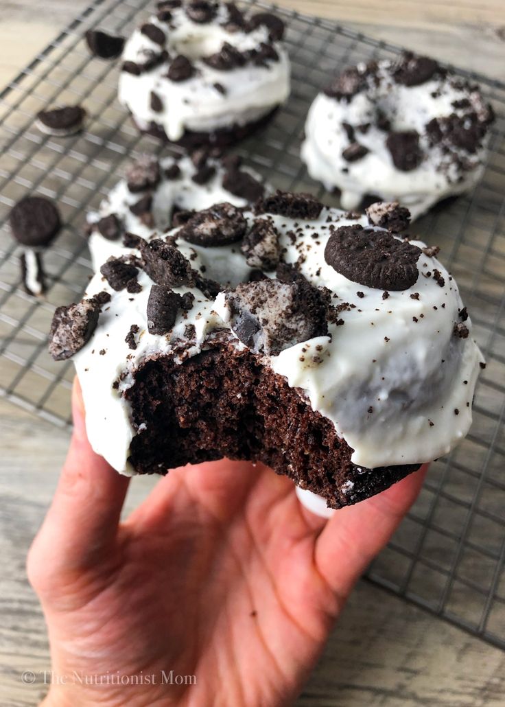 someone is holding up a chocolate cookie with white frosting and oreo cookies on top