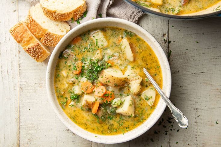 two bowls of soup with bread on the side