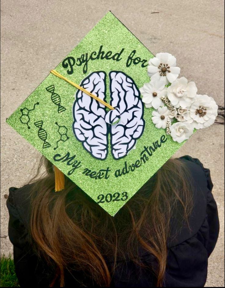 College graduation cap topper. Green glitter background with a brain in the middle. One side features molecules and the other side is flowers. Text on the cap says “psyched for my next adventure” with the graduation year on the bottom Psychology Senior Pictures, Psychology Degree Photoshoot, Double Major Graduation Cap, Psychology Themed Graduation Party, Graduation Caps For Psychology Majors, Brain Graduation Cap, School Psychology Graduation Cap, Psychology Major Graduation Pictures, Graduation Cap Ideas Psychology