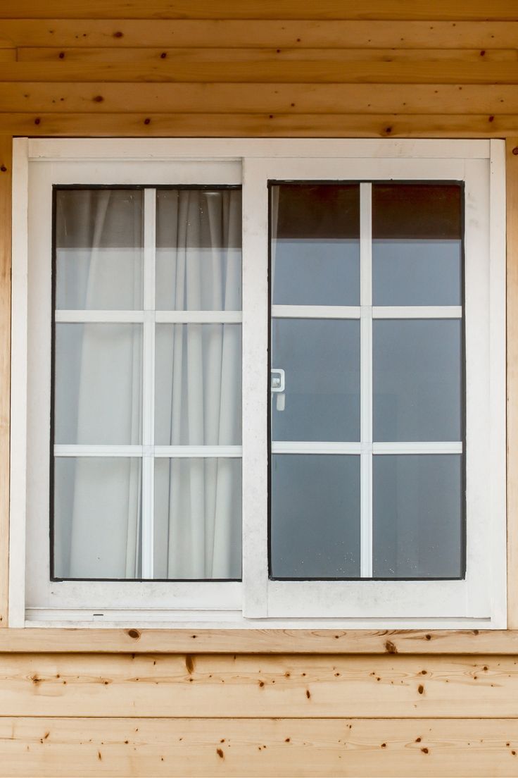 a cat sitting on the window sill of a wooden house