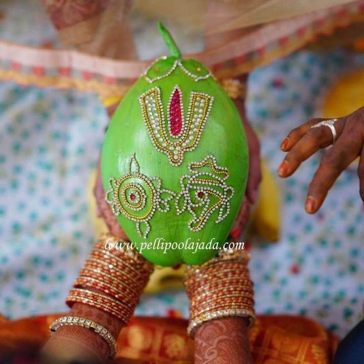 a woman's hands holding a green decorated egg