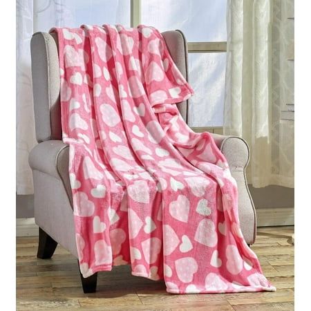 a pink and white heart print blanket sitting on top of a chair next to a window