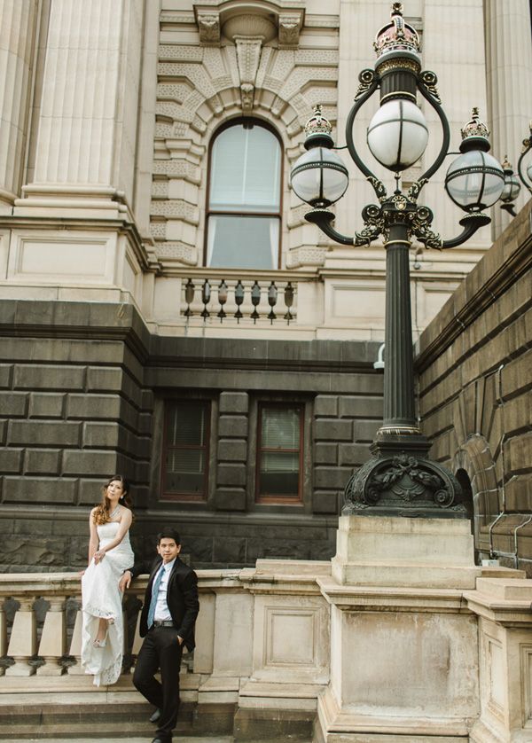 a man and woman standing next to each other in front of a light pole on steps